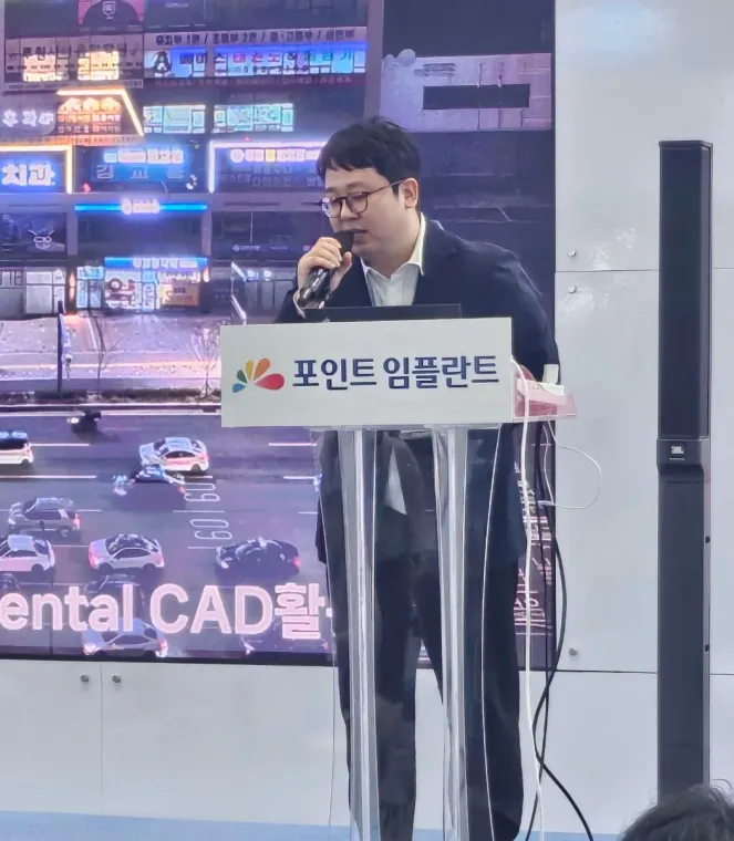 포인트 임플란트 연단에서 마이크를 잡고 강연하는 김교락 대표원장